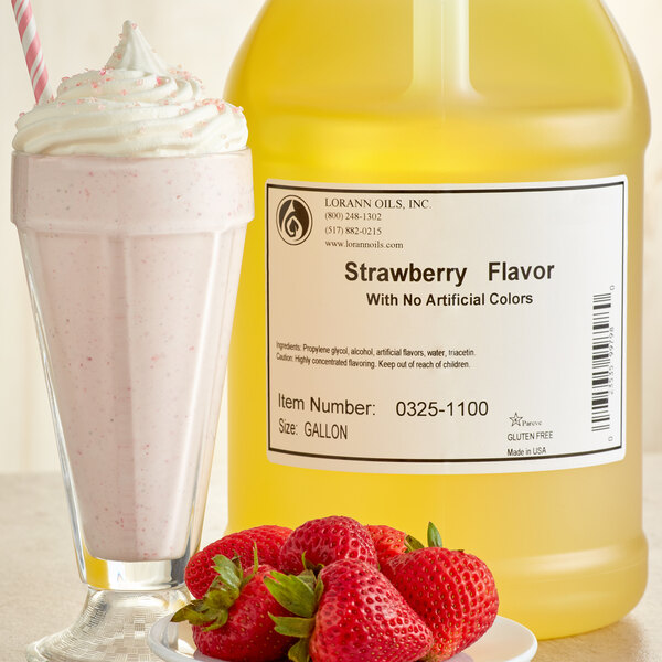 A glass of milkshake with LorAnn Oils No Color Added Strawberry Super Strength Flavor next to a bottle of the liquid.