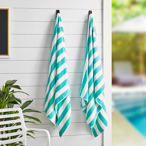 Two Monarch Brands California Cabana green striped pool towels hanging on a wall.