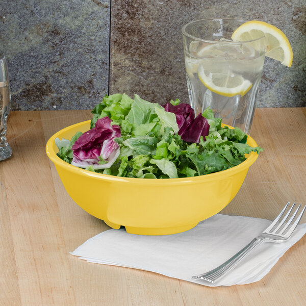 A yellow Thunder Group melamine bowl filled with salad on a table.