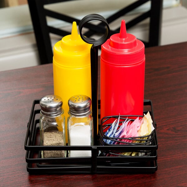 A rectangular black wrought iron condiment caddy holding condiments on a table.