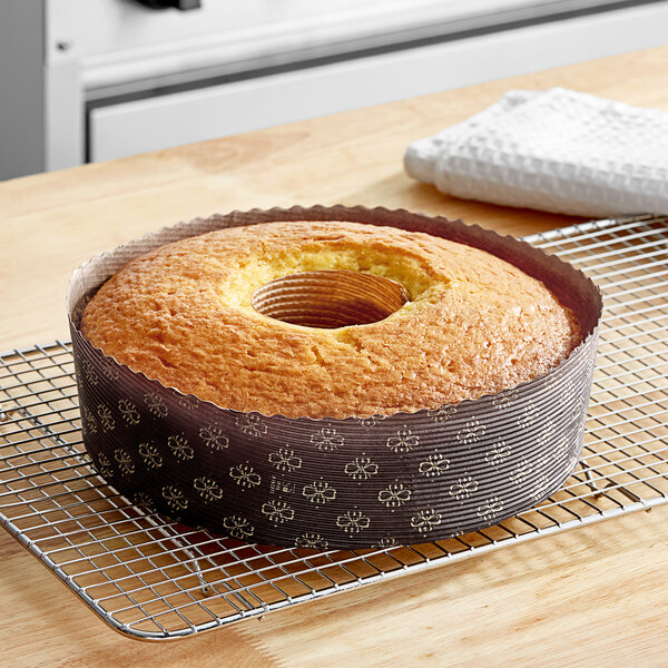 A cake in a Novacart corrugated kraft paper baking ring mold on a cooling rack.