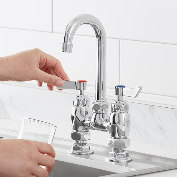 A hand opening a Waterloo deck mount faucet over a sink.