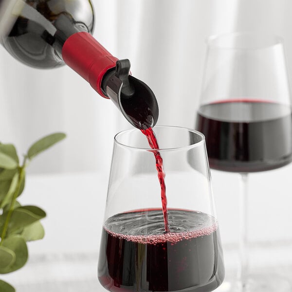 A Rabbit steel wine pourer on a wine bottle being used to pour red wine into a glass.