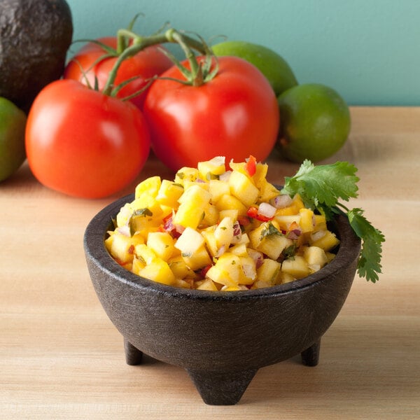 A charcoal polypropylene Molcajete filled with fruit salsa, tomatoes, and yellow fruit.