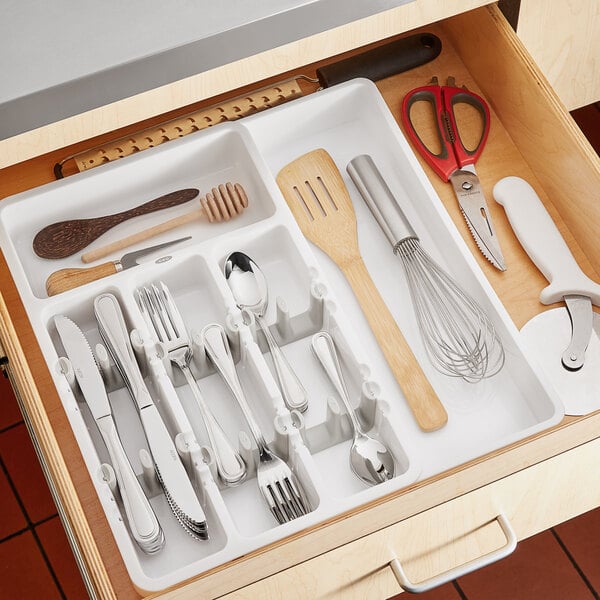 A drawer with OXO Good Grips white expandable utensil organizer holding utensils and other kitchen tools.