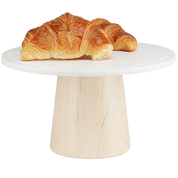 A Cal-Mil maple wood cake stand with croissants on it.
