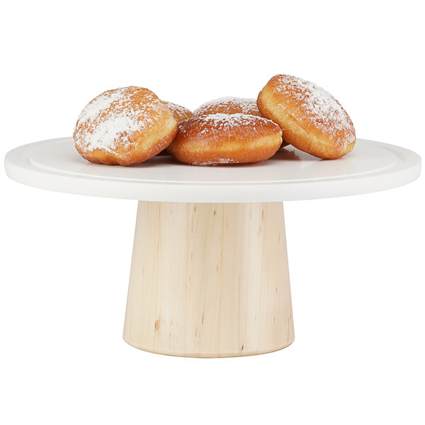 A Cal-Mil maple wood cake stand with doughnuts on it.