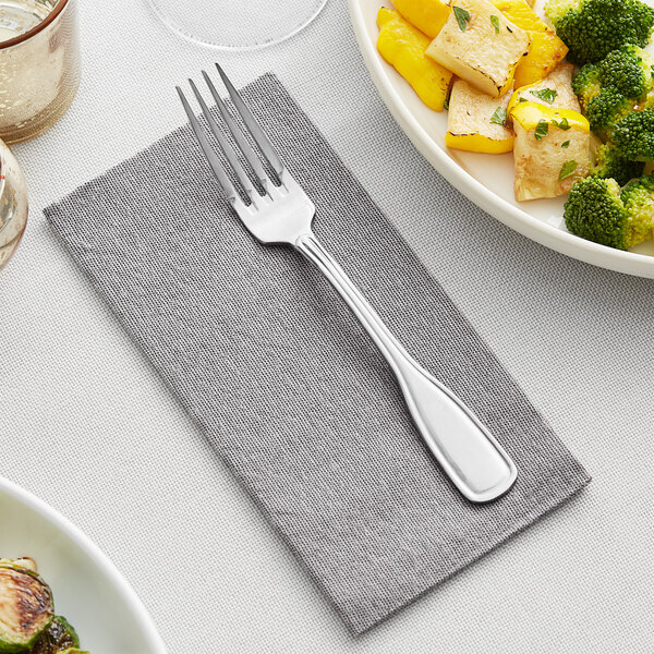 A fork on a Hoffmaster linen-like dinner napkin next to a plate of food.