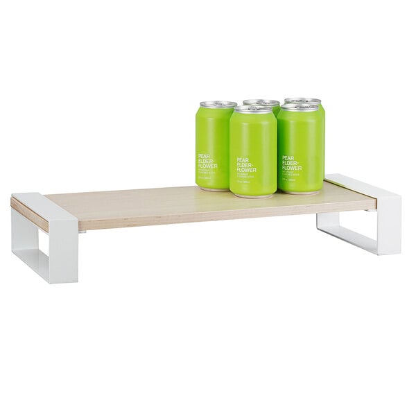 A wooden shelf holding a group of green cans of soda.