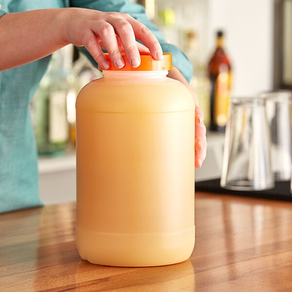 A woman pouring orange juice from a Choice plastic container with an orange cap.