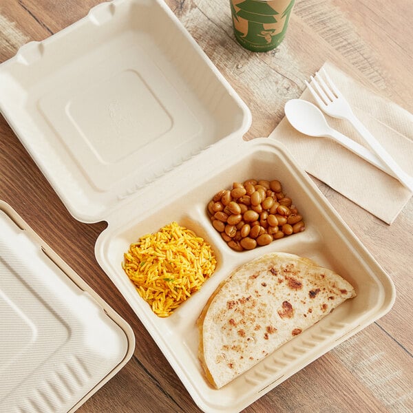 A Footprint Bagasse take-out container with food and a fork on a table.