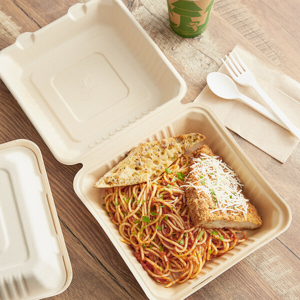 A Footprint Bagasse take-out container with food on a table.