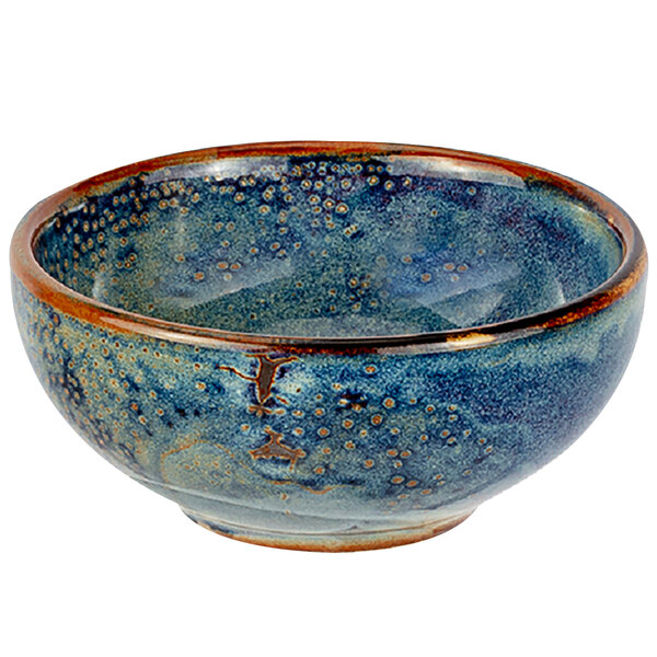 A blue bowl with brown speckles on a table.
