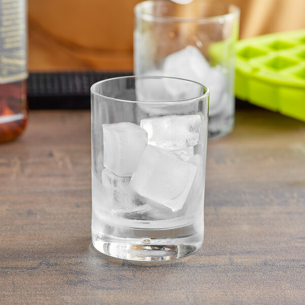 A glass with Fox Run lime ice cubes on a table.