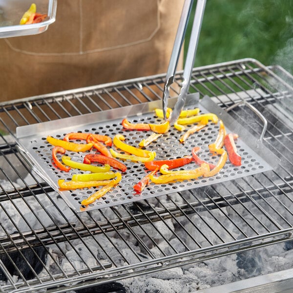A person grilling vegetables on an Outset stainless steel grill tray.