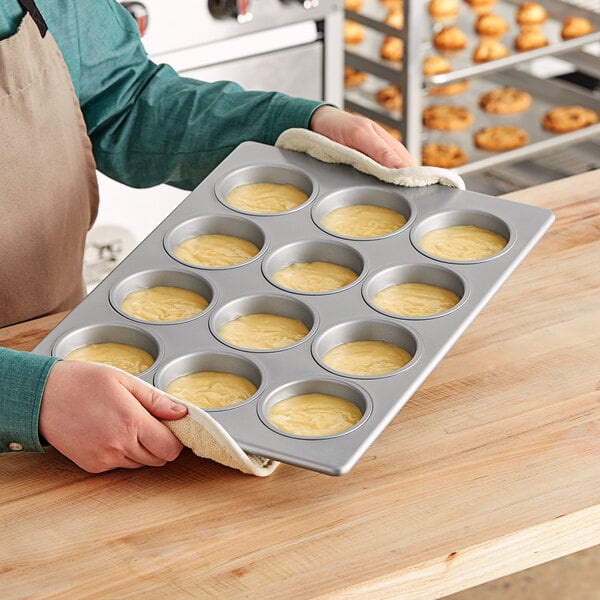 A person holding a Baker's Mark jumbo muffin pan filled with muffins.