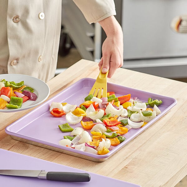 A person cutting vegetables on a Baker's Mark purple sheet pan.