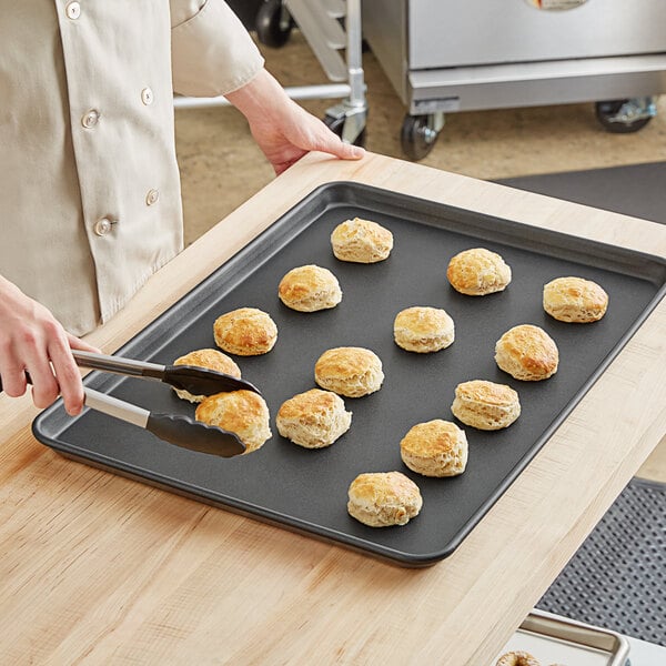 A person using a Baker's Mark non-stick sheet pan to cut biscuits.