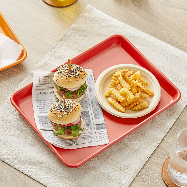 A Baker's Mark red non-stick aluminum tray with two burgers and fries on it.