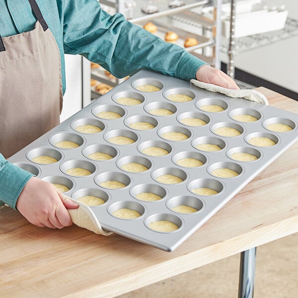 A person holding a Baker's Mark Muffin / Cupcake Pan filled with muffins.