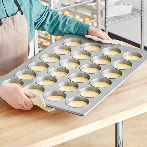 A woman holding a Baker's Mark jumbo muffin pan filled with muffins.