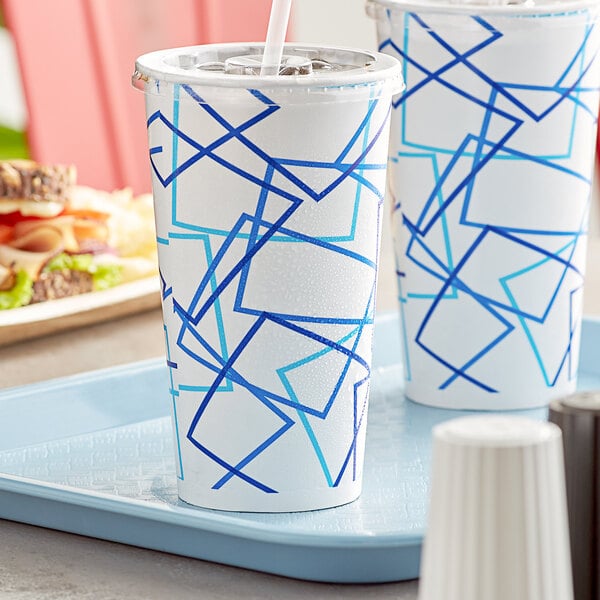 A white Choice paper cold cup with blue lines filled with soda on a tray with another white Choice paper cold cup filled with soda.