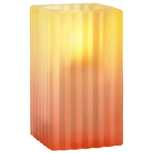 A Sterno Sunset Gradient ribbed glass candle holder with a lit orange and yellow striped candle inside.