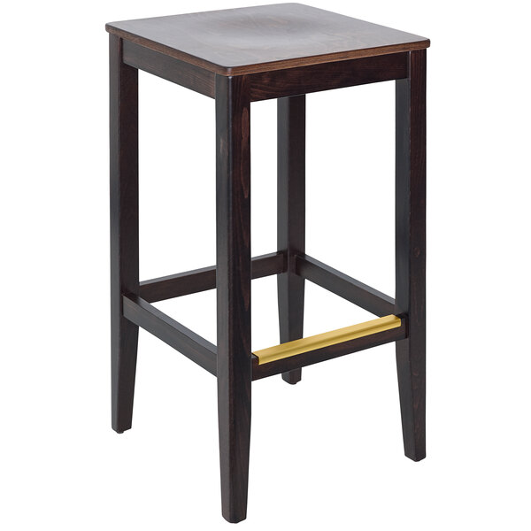 A BFM Seating dark walnut beechwood barstool with a wood seat on a table in a bar.