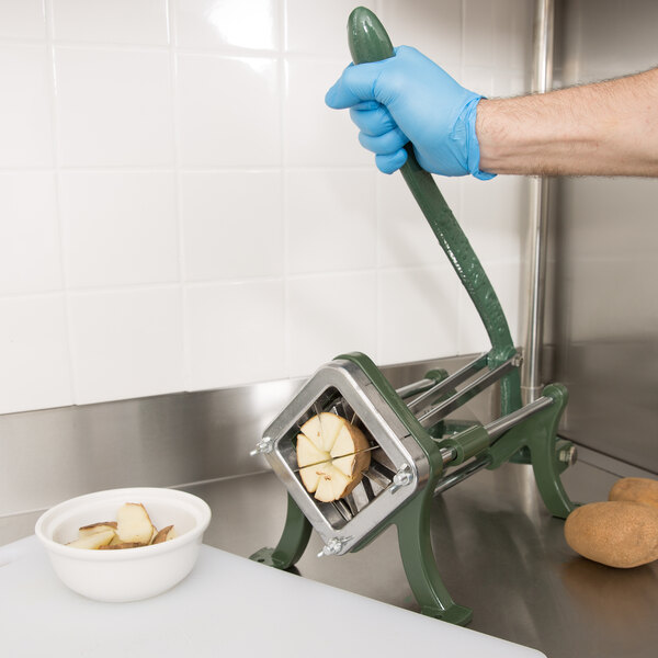 A person wearing blue gloves uses a Choice Prep Potato Wedge Cutter to slice potatoes.