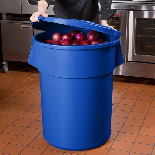 A woman opening a blue 55 gallon ingredient storage bin to reveal red onions.