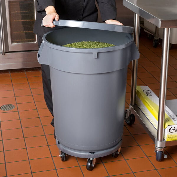 A woman holding a large gray Mobile Ingredient Storage Bin in a school kitchen.
