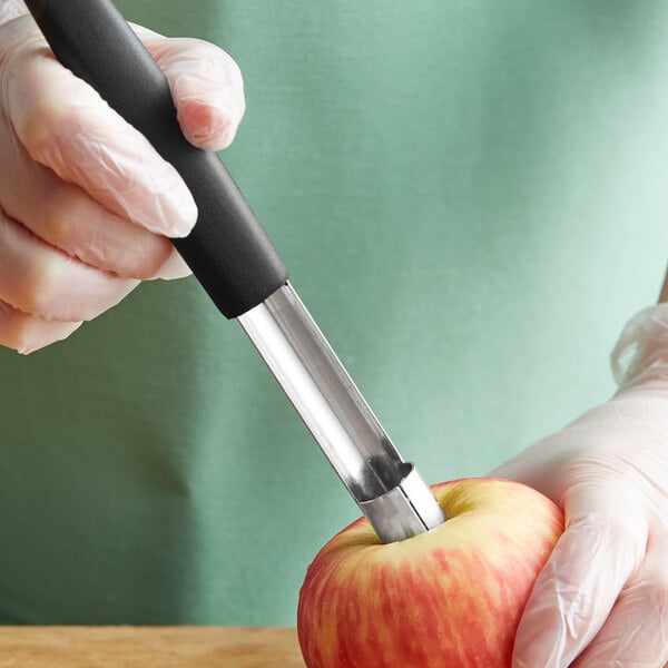 A hand using a Mercer Culinary apple corer to cut an apple.