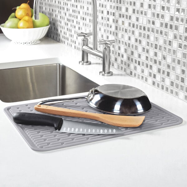 An OXO Good Grips silicone drying mat with a knife and bowl on it.