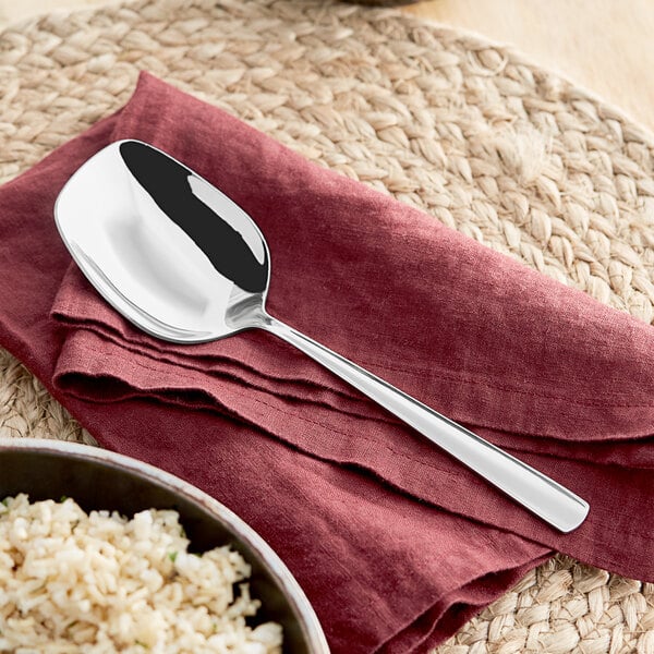 An Emperor's Select stainless steel serving spoon on a napkin next to a bowl of rice.
