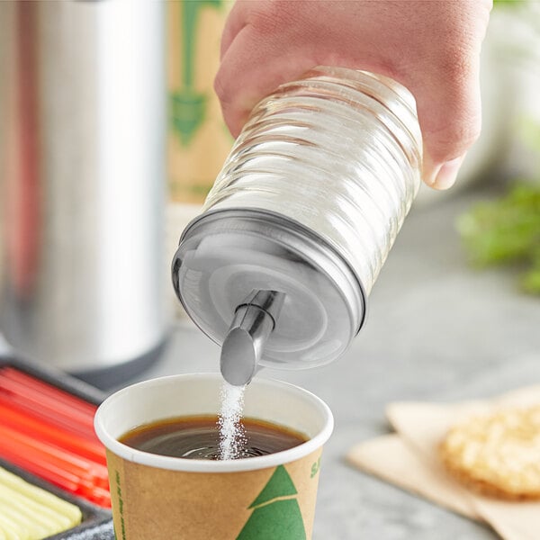 A hand pouring sugar from a Tablecraft beehive sugar pourer into a cup of coffee.