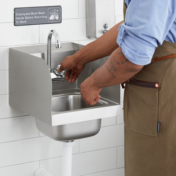 A man wearing an apron using a Steelton wall mounted hand sink with gooseneck faucet.
