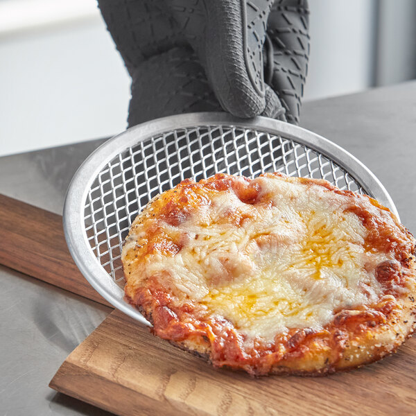 A cheese pizza on a Choice aluminum pizza screen on a table.