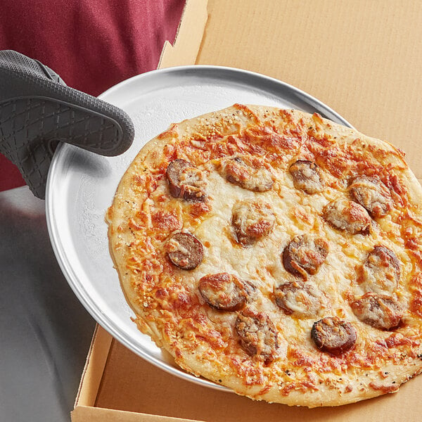 A pizza on a Choice aluminum coupe pizza pan.