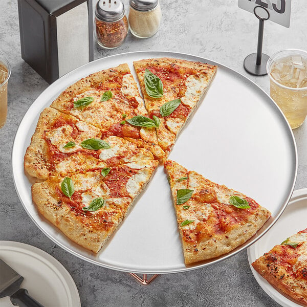 A pizza on a Choice aluminum coupe pizza pan with a slice missing.