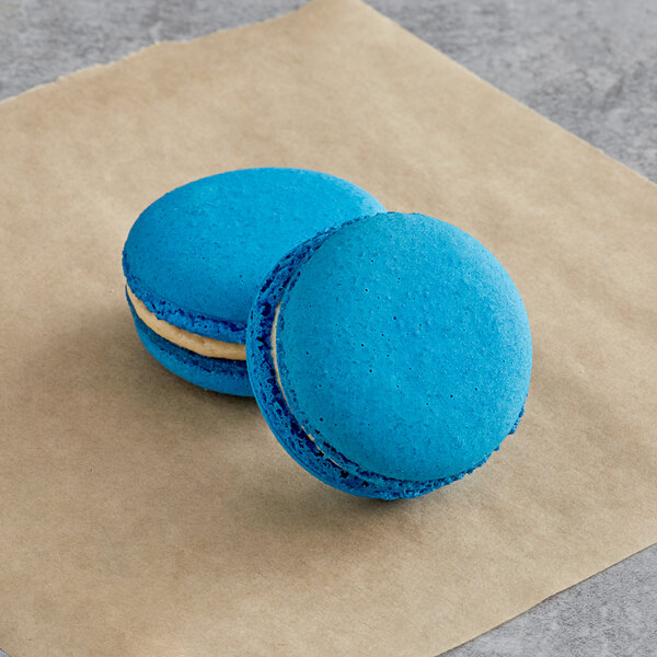 Two blue Macaron Centrale macarons on a piece of paper.