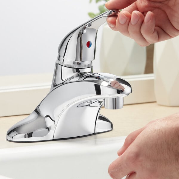 A person's hand using a Regency deck-mounted faucet to wash their hands.