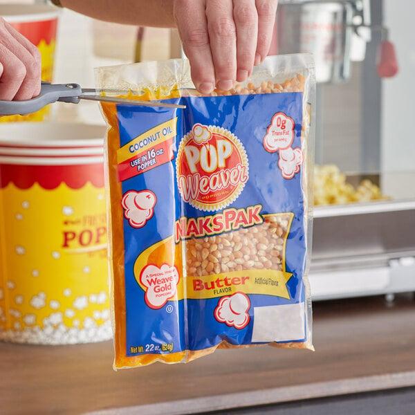 A person using a Pop Weaver All-In-One Naks Pak Popcorn Kit to fill a plastic bag with popcorn.