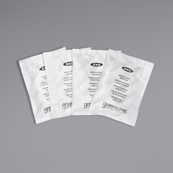 A group of four white OXO GreenSaver carbon filter packets with black text.