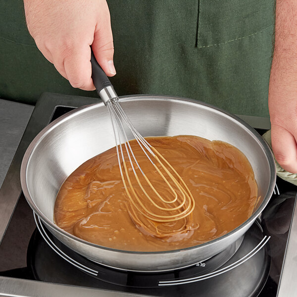 An OXO Good Grips flat whisk stirring brown liquid in a bowl.