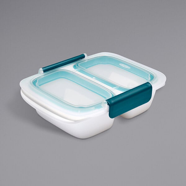 A white OXO rectangular plastic food container with two trays on top.