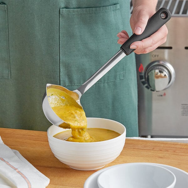 A person using an OXO Good Grips ladle to pour soup into a bowl.