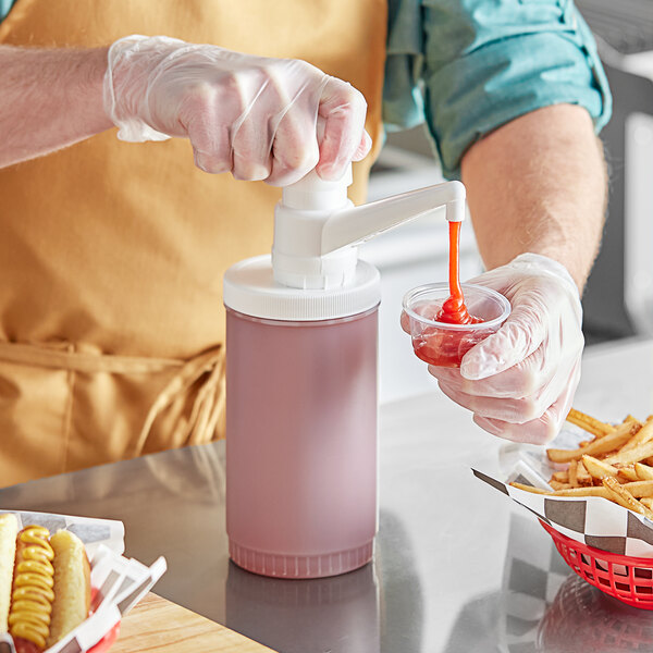 A person using a Choice plastic condiment pump to pour ketchup into a plastic container of fries.