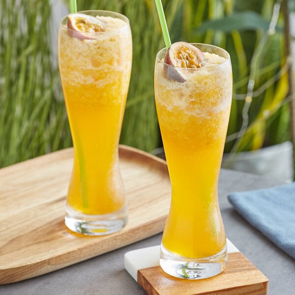 A wooden tray holding two glasses of Fanale Passion Fruit syrup with straws.