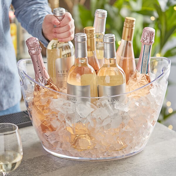 A group of bottles in a Choice large plastic oval wine bucket filled with ice.