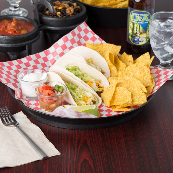 A table with a plate of tacos and a HS Inc. Charcoal Polypropylene deli server full of tacos and chips.